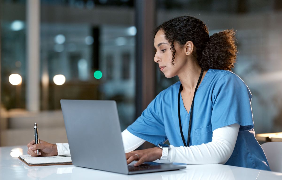 caregiver reviewing data on laptop from 24/7 senior monitoring service."