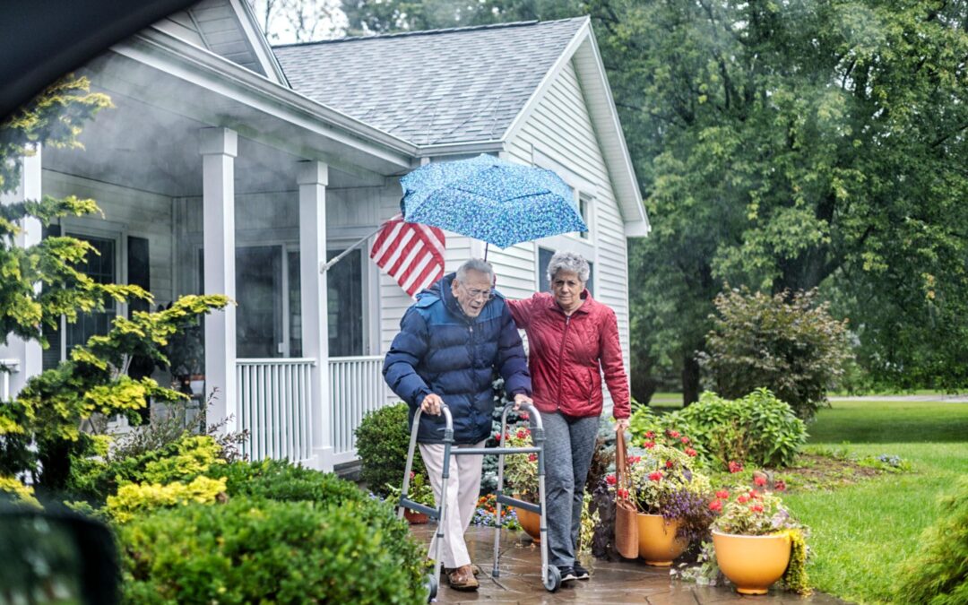 spring fall prevention tips Connecticut caregiver helping senior safely enter home on a rainy day